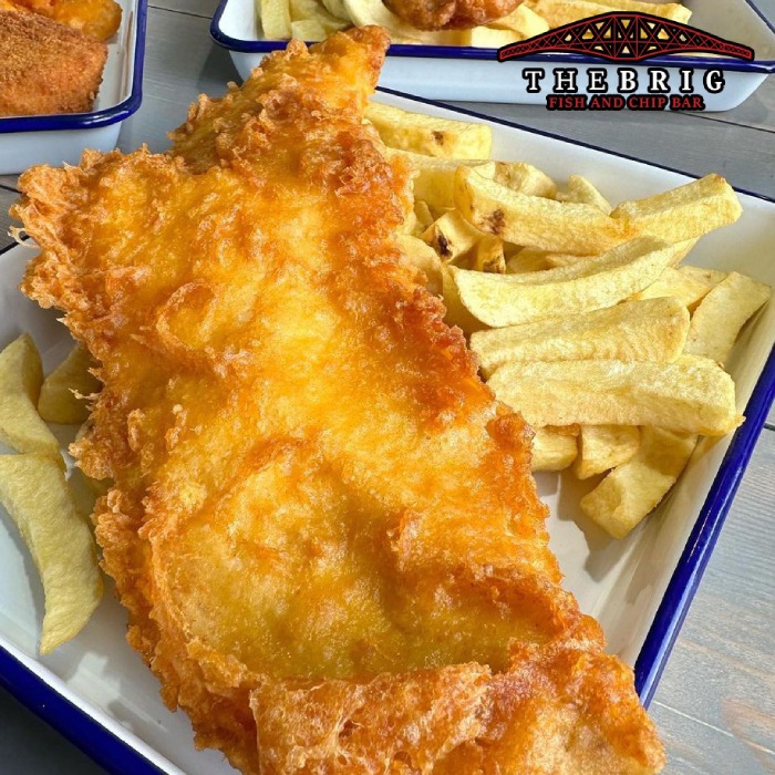 a golden fried fish with crispy chips on a plate served at the brig 
takeaway in Dunfermline